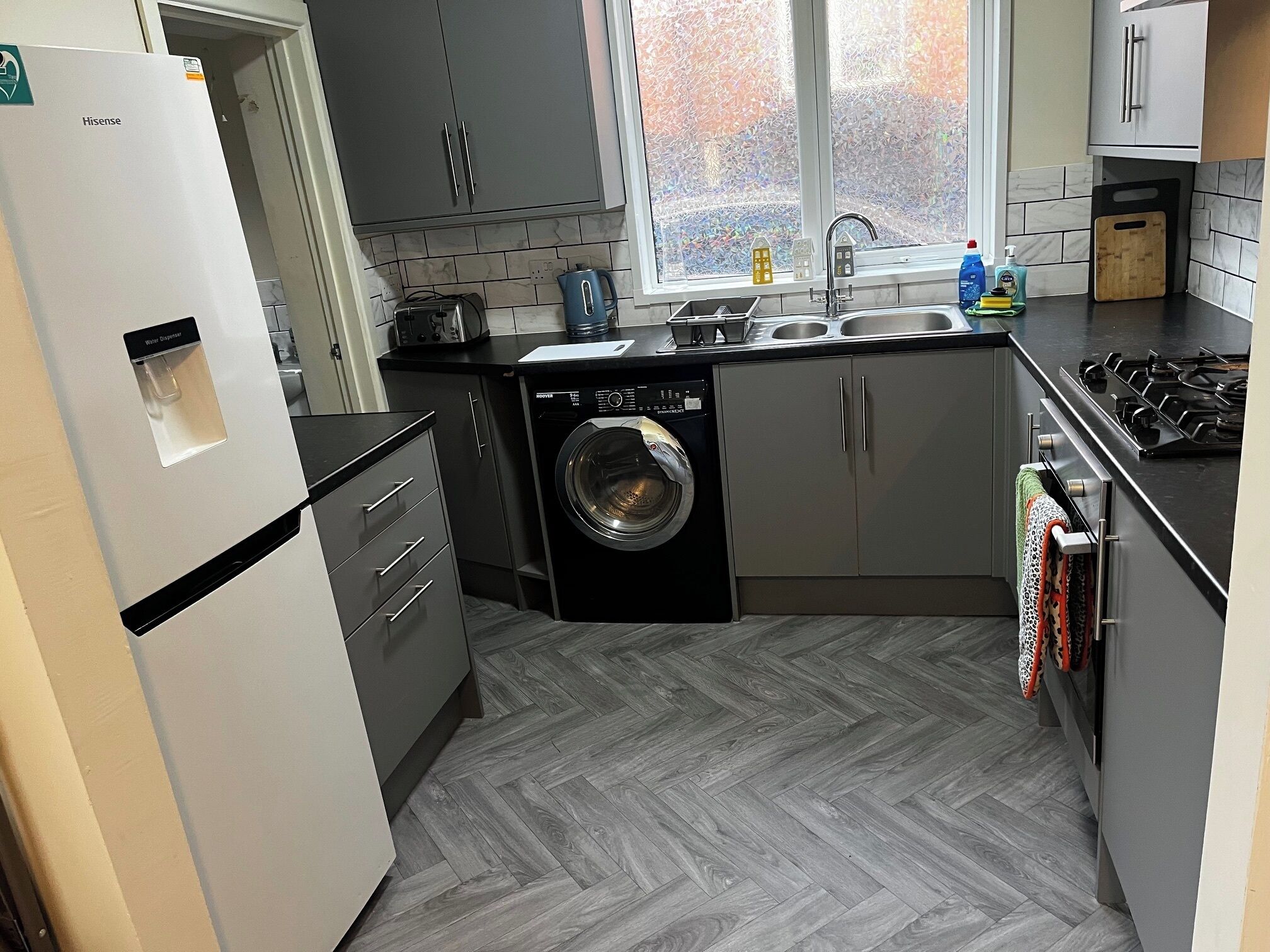A compact kitchen with a washing machine, a sink, and a stove.