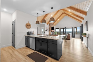 A modern kitchen with a central island, black cabinetry, and pendant lighting. - Two Luxury Indoor Fireplaces! By Table Rock Lake! (Branson)