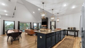 A spacious kitchen with a large island, dark cabinetry, and modern pendant lighting. - Fire Pit! Hot Tub! Stunning Views! Two Fireplaces! (Branson)