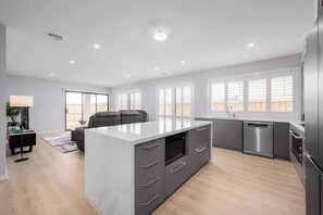 A modern kitchen with a central island, grey cabinetry, and stainless steel appliances. - Bella Brand New Modern Stylish 4BR Home (Clyde)