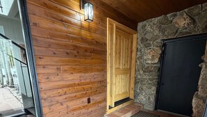 Un interior de madera con una pared de piedra, una puerta de madera y suelo de baldosas.