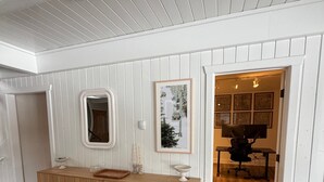 Un interior moderno con una consola de madera, un espejo y obras de arte enmarcadas en la pared.