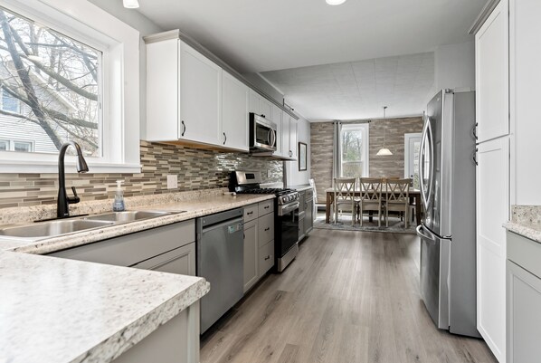 A modern kitchen with stainless steel appliances, a tiled backsplash, and a dining area with a wooden table and chairs.