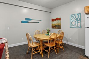 Un coin repas avec une table et des chaises en bois, une petite plante et deux œuvres d’art murales.