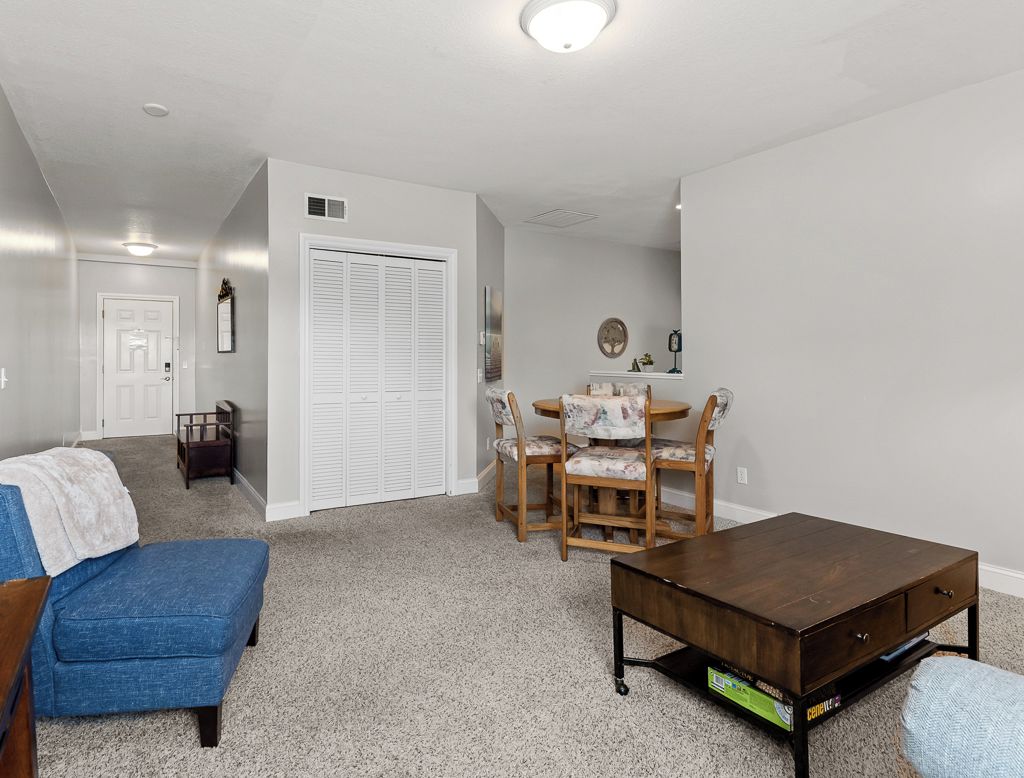 Un soggiorno con un divano blu, un tavolino in legno e un'area pranzo con un tavolo rotondo e sedie.