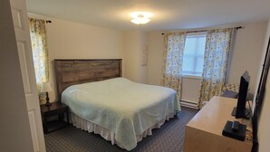 A bedroom with a bed, a desk, and a nightstand.