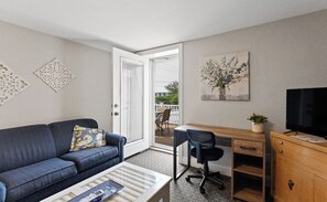 A modern living room with a sofa, coffee table, desk, and television.