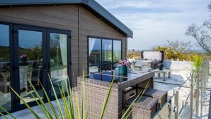 Una casa moderna con amplios ventanales, mobiliario de exterior y un jacuzzi.