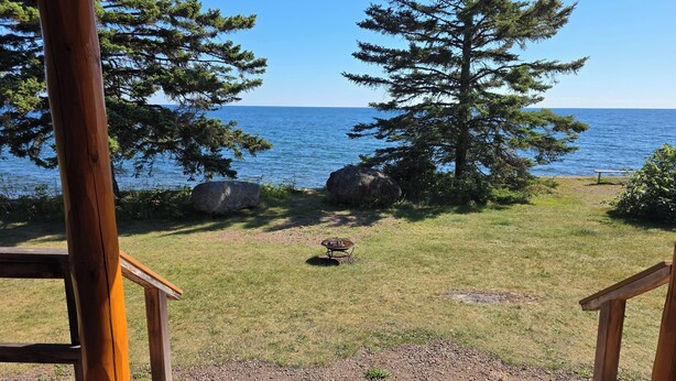 A wooden deck with a view of a lake and trees. - Lake Superior Log Cabin - Wake up to Waves! (Lutsen)