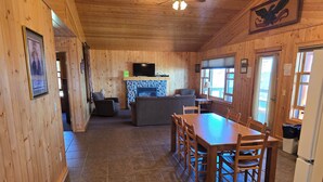 A wooden interior with a dining area, a fireplace, and a television. - Lake Superior Log Cabin - Wake up to Waves! (Lutsen)