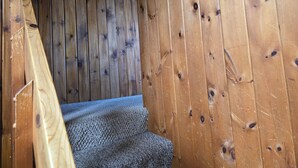 A wooden staircase with a textured carpet leading up to a room with wooden walls and a framed picture. - Lake Superior Log Cabin - Wave Watching Delight! (Lutsen)