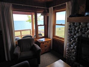 Een gezellige kamer met uitzicht op het water, een stenen open haard en een houten bureau met stoel.