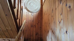 A wooden staircase with a woven rug hanging from the ceiling. - Lake Superior Log Cabin - Wave Watching Delight! (Lutsen)
