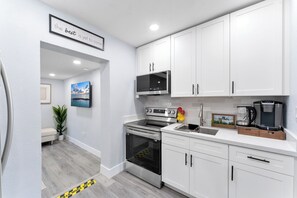 A modern kitchen with white cabinets, stainless steel appliances, and a coffee maker. - 3BR 2BA Middle River Palm House in Fort Lauderdale (Fort Lauderdale)