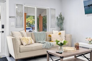 A living room with a beige sofa, a coffee table, and a window with blinds. - 3BR 2BA Middle River Palm House in Fort Lauderdale (Fort Lauderdale)