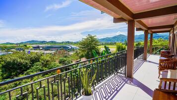 A balcony with a view of a modern building and lush greenery.