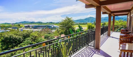 A balcony with a view of a modern building and lush greenery.