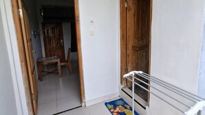 A hallway with a tiled floor, wooden doors, a metal handrail, and a colorful mat. - Golo Tango Homestay (Labuan Bajo)