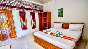 A bedroom with a wooden bed, a wardrobe, a desk, and a painting on the wall. - Golo Tango Homestay (Labuan Bajo)