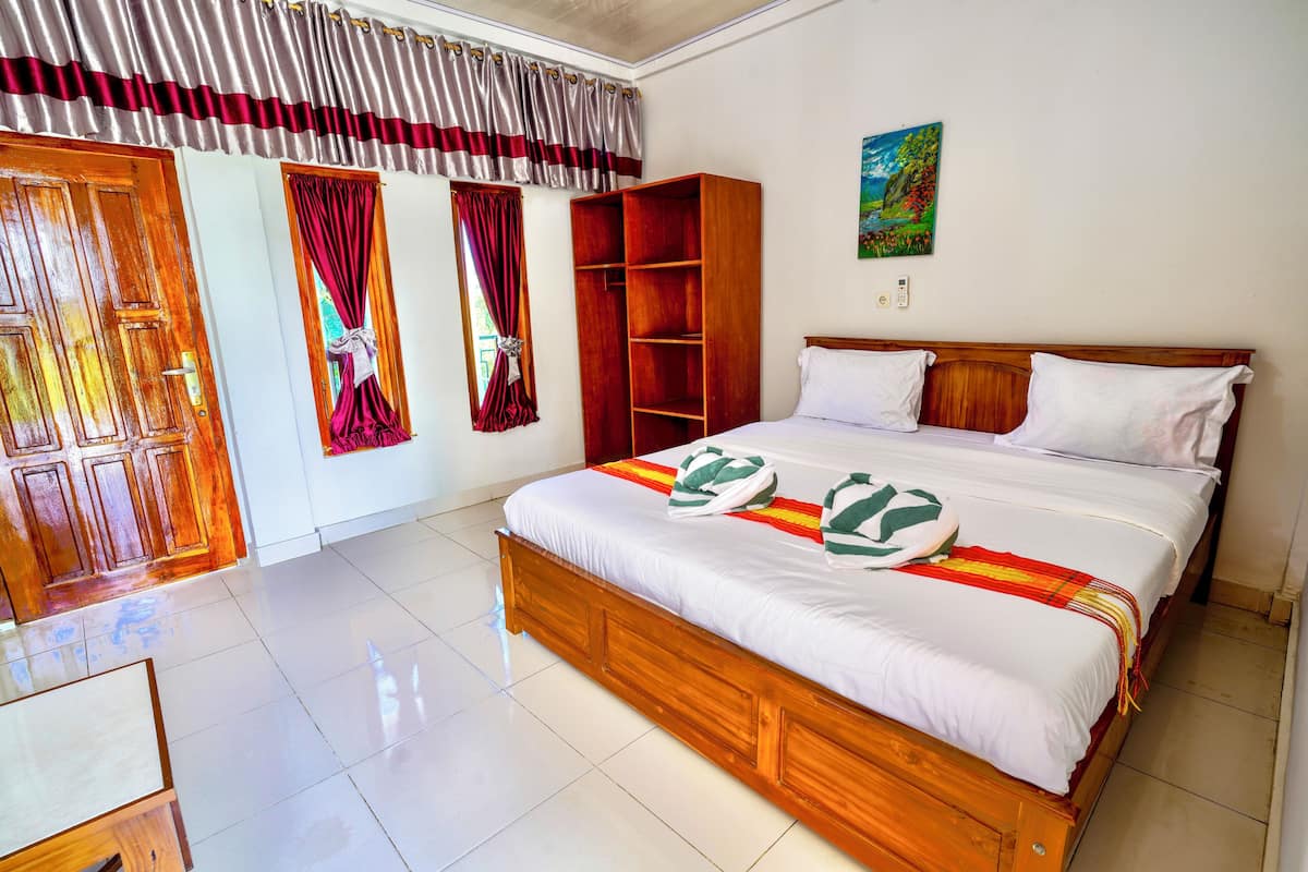 A bedroom with a wooden bed, a wardrobe, a desk, and a painting on the wall.