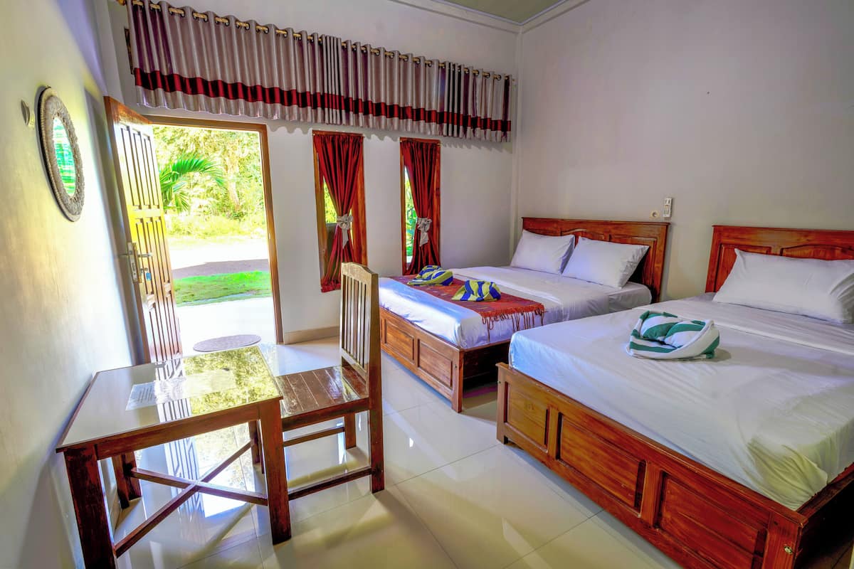 A room with two wooden beds, a small table, and a chair.