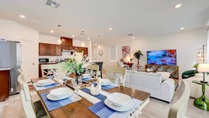 Ein modernes Wohnzimmer mit Essbereich, Küche und Fernseher.