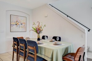 A dining area with a table set for four, chairs, a vase with flowers, and a painting on the wall. - Comfy Stay7 Beds| Close to Strip & Attraction (Enterprise)