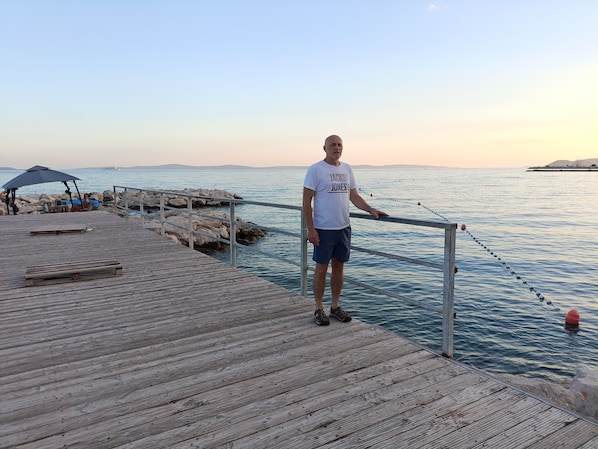A wooden pier extending into calm waters with a person standing at the end.