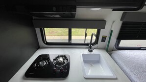 A kitchenette with a stove, sink, and window view. - Welcome to Cozy by the Coast! Just steps from the beach, ocean is calling you! (Surfside Beach)