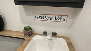 A bathroom with a white sink, wooden countertop, and a mirror above. A sign above the sink reads "WASH. SOAK. Relax." - Welcome to Cozy by the Coast! Just steps from the beach, ocean is calling you! (Surfside Beach)