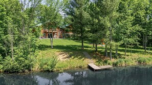 Un chalet au bord du lac, doté d’un quai, et entouré d’une végétation luxuriante et d’arbres.