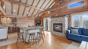 Una cocina amplia con una isla central, taburetes de madera y una chimenea de piedra.