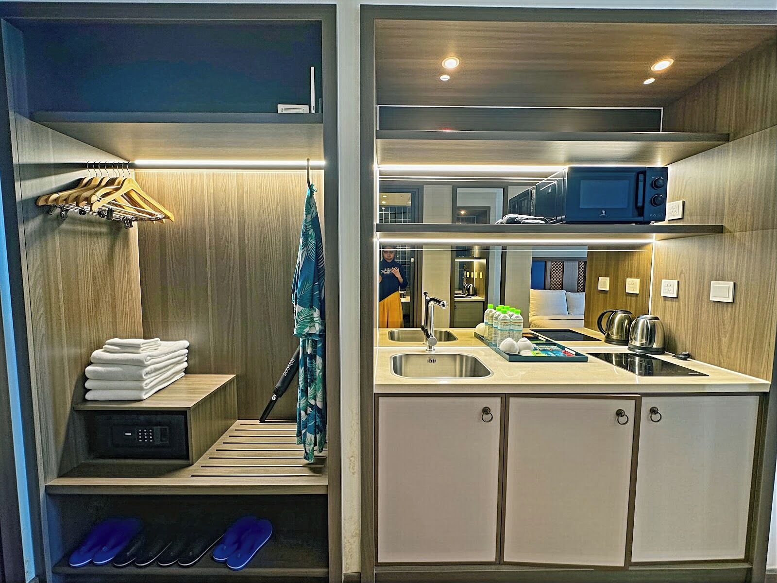 Une chambre d’hôtel compacte comprenant un coin cuisine, une zone douche et un petit espace salon.