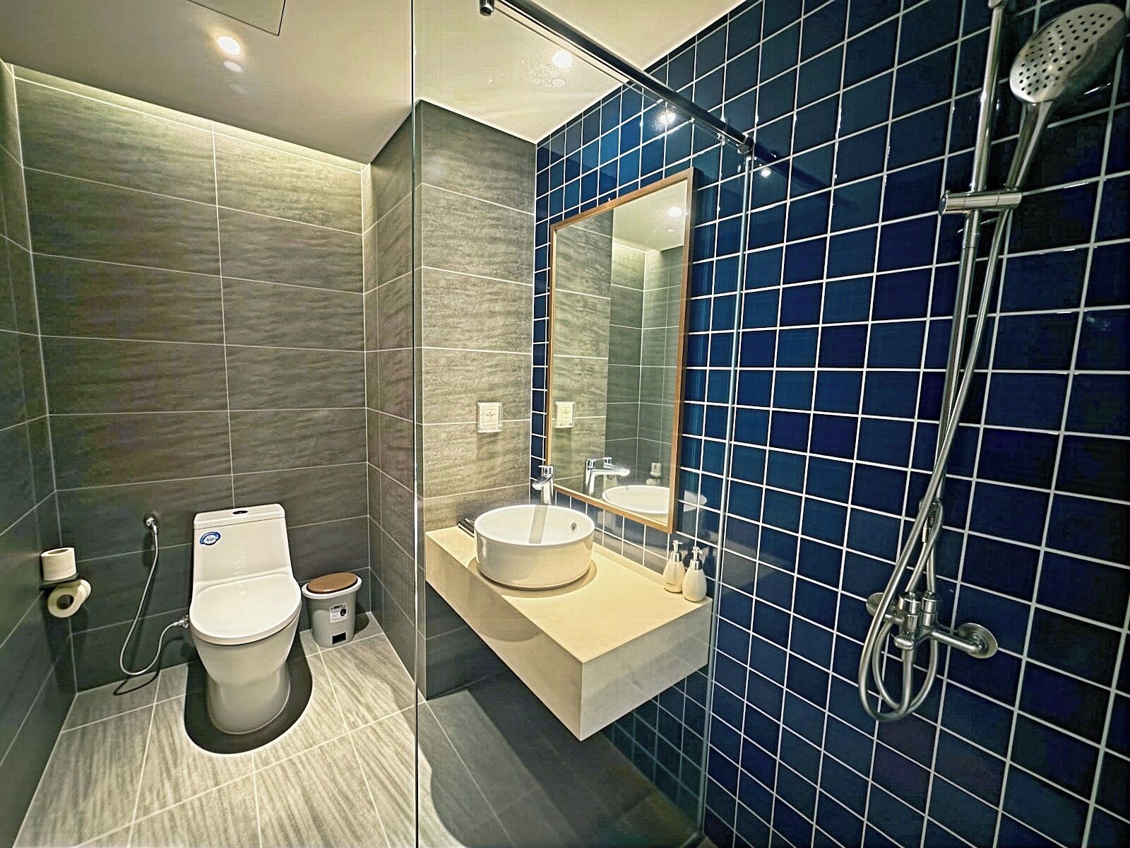 A modern bathroom with a toilet, bidet, sink, and shower.