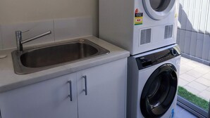 Uma lavanderia compacta com máquina de lavar, pia e armário pequeno.