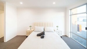 Quarto de hotel com uma cama grande, duas mesas de cabeceira, uma janela e uma porta.