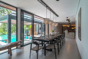 A modern dining area with a long table, black chairs, and a chandelier. - Kiena Ubud (Ubud)