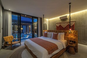 A modern bedroom with a large bed, a wooden nightstand, and a view of a pool. - Kiena Ubud (Ubud)