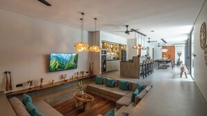 A modern living room with a large TV, wooden flooring, and a dining area in the background. - Kiena Ubud (Ubud)