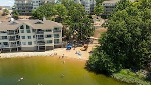 A multi-story building with balconies, a sandy beach area, and a body of water. - Beach Area, 2 Pools, Pet-Friendly Condo at 20.5mm (Osage Beach)