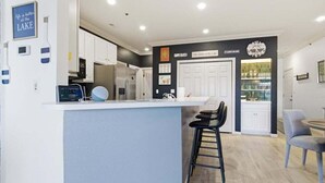 Een moderne keuken met een bar, witte kasten en een accentmuur in het zwart.