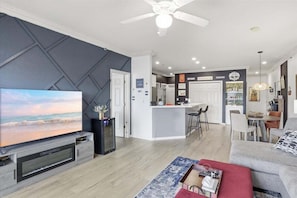 Un salon moderne doté d’un téléviseur à écran plat, d’un ventilateur de plafond et d’un coin repas avec un bar.