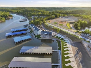 A riverside hotel with docked boats, a parking area, and a landscaped garden.
