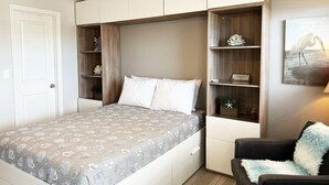 Un dormitori amb un llit, prestatges integrades, un ventilador de sostre i un quadre a la paret.