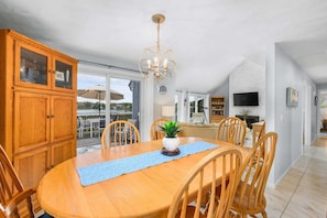 A dining area with a wooden table, chairs, and a chandelier. - Waterfront Escape with Stunning Views on Bass River (West Dennis)