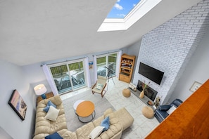 A modern living room with a sofa, coffee table, and fireplace. - Waterfront Escape with Stunning Views on Bass River (West Dennis)