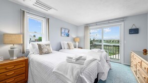 Un dormitorio con dos camas, un aparador, una lámpara y vistas al exterior.