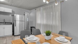 Una cucina moderna con mobili bianchi, un frigorifero in acciaio inossidabile e un'area pranzo con un tavolo in legno apparecchiato per quattro persone.