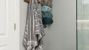 A bathroom with a white door, a black stool, a marble-patterned rug, and towels on a rack. - 3-bedroom house in pleasant Paso Robles with cool vibes (Paso Robles)
