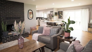 A modern living room with a fireplace, a dining area, and a kitchen in the background. - 3-bedroom house in pleasant Paso Robles with cool vibes (Paso Robles)